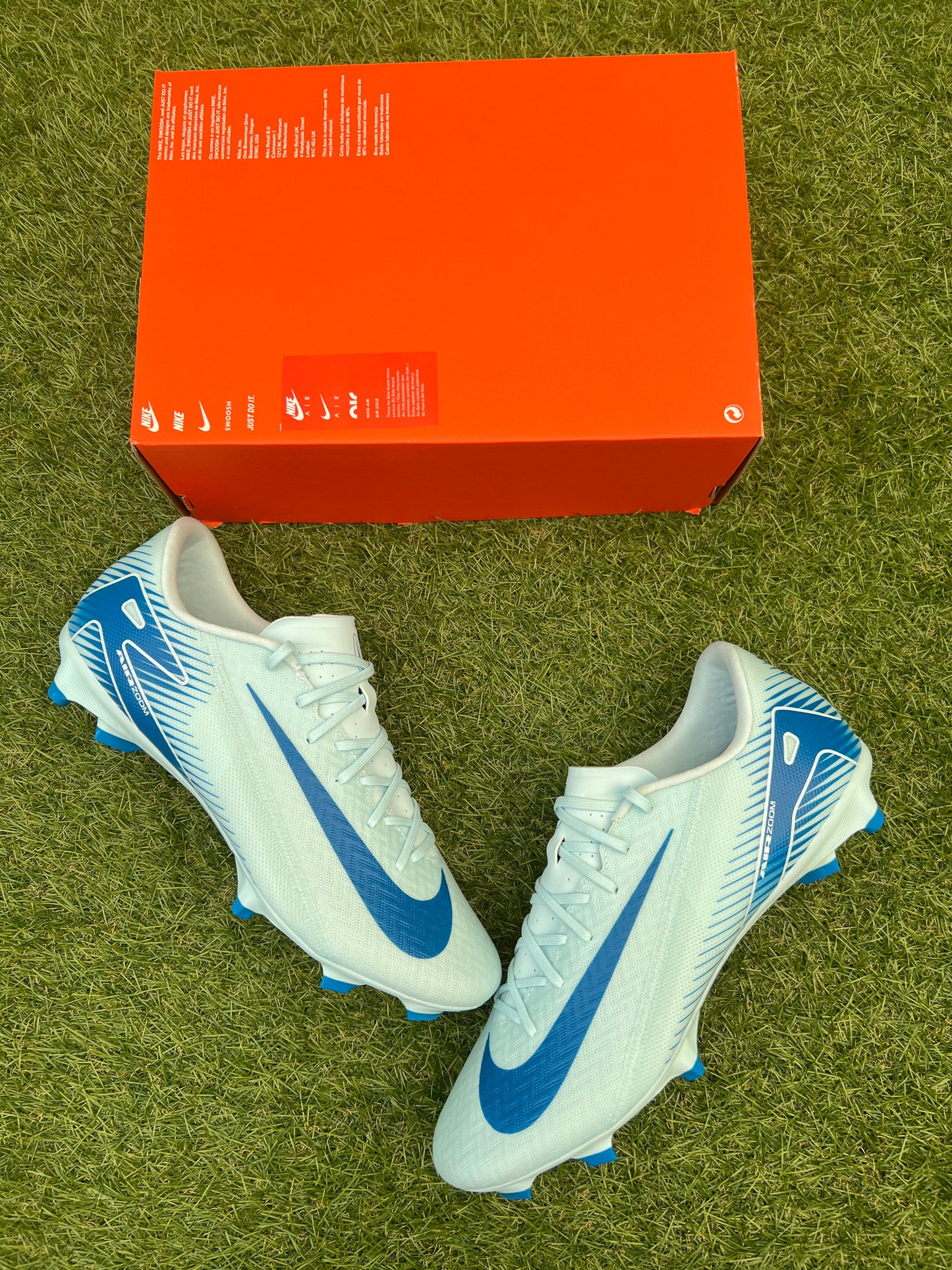 Nike Air Zoom Mercurial Vapor 16 Academy FG/MG football boots in Glacier Blue and Blue Orbit – lightweight synthetic upper with angular soleplate, designed for firm and artificial ground. Displayed on grass background, available at Sneaker Dyl.