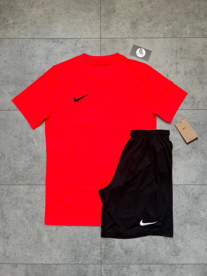 Flat-lay of Nike Dri Fit set featuring a bold bright crimson slim-fit t-shirt and black shorts with tags, displayed on a tiled surface.