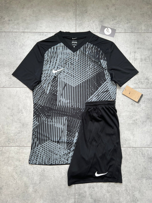 Flat-lay of Nike Dri Fit Precision set featuring a black and cool grey geometric t-shirt and solid black shorts with tags, on a grey tile background.
