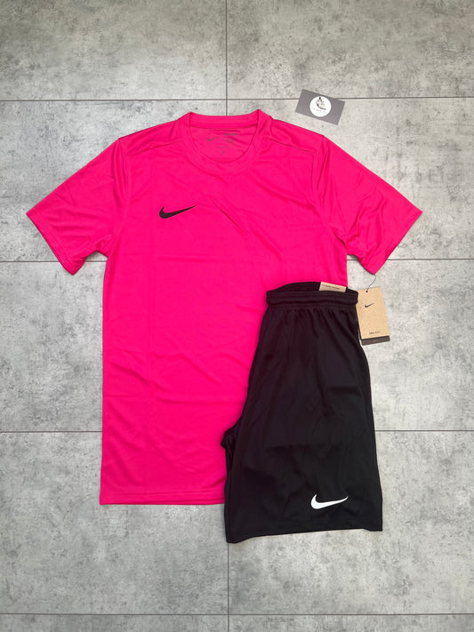 Flat-lay of Nike Dri Fit set featuring a vivid pink slim-fit t-shirt and black shorts with tags, laid out on a grey tiled background.