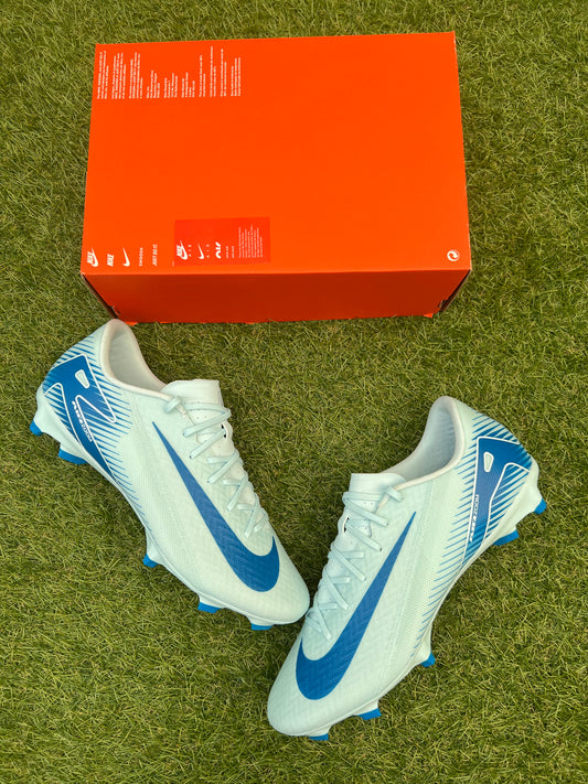 Nike Air Zoom Mercurial Vapor 16 Academy FG/MG football boots in Glacier Blue and Blue Orbit – lightweight synthetic upper with angular soleplate, designed for firm and artificial ground. Displayed on grass background, available at Sneaker Dyl.